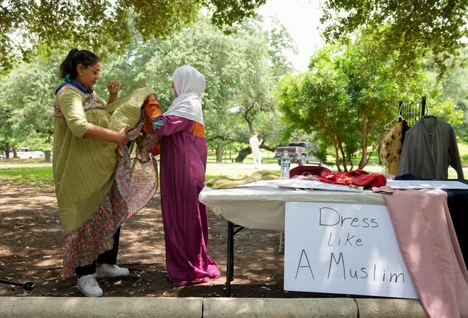 Andrea Gonzalez, right, dresses Lexie Tucker, a non-Muslim, in Muslim clothes at a “Dress Like a Muslim” booth at the 3rd Annual Eid Celebration and Friday Prayer at the Capitol Friday April 19, 2024. Every year after Muslims finish fasting for a month during Ramadan, they gather for Eid al-Fitr, the festival of breaking the fast. The event had Middle Eastern food, henna design, Arabic calligraphy and an art display.
