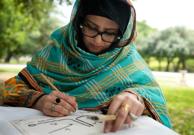 Sanam Nadeem does Arabic calligraphy at the 3rd Annual Eid Celebration and Friday Prayer at the Capitol Friday April 19, 2024. Every year after Muslims finish fasting for a month during Ramadan, they gather for Eid al-Fitr, the festival of breaking the fast. The event had Middle Eastern food, henna design, Arabic calligraphy and an art display.