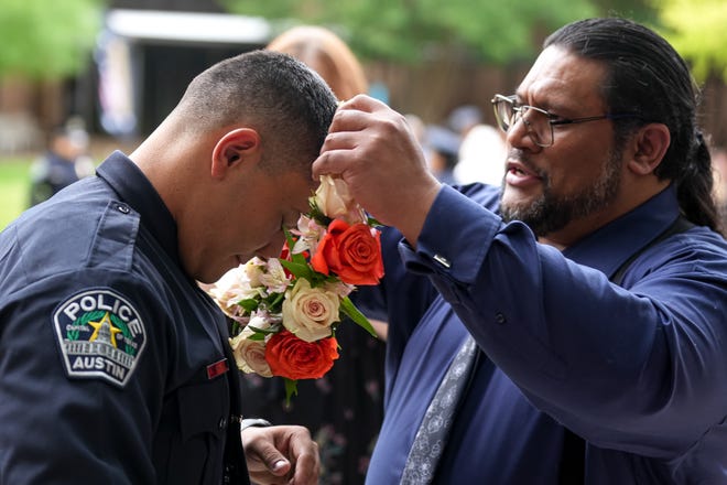 Joe Taito places flowers around the neck of his son and graduation officer Joey Taito after the graduation ceremony for the Austin Police Department’s 151st Cadet Class at Bannockburn Church on Friday, April 19, 2024 in Austin.