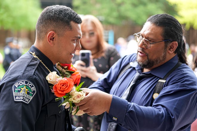 Joe Taito places flowers around the neck of his son and graduation officer Joey Taito after the graduation ceremony for the Austin Police Department’s 151st Cadet Class at Bannockburn Church on Friday, April 19, 2024 in Austin.