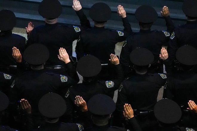 Graduating officers hold up their right hand to take their oath of service at the graduation ceremony for the Austin Police Department’s 151st Cadet Class at Bannockburn Church on Friday, April 19, 2024 in Austin.
