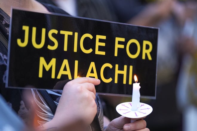 A community member holds a sign and candle at a vigil for Malachi Williams outside the San Marcos Public Library on Thursday, April 25, 2024 in San Marcos, Texas. Williams was killed by San Marcos Police on Thursday, April 11, 2024.